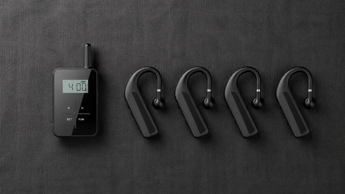 Flat lay of a complete wireless tour guide system including transmitter multiple receivers earphones and charging dock arranged on a dark linen background Flat lay of a complete wireless tour guide system including transmitter multiple receivers earphones and charging dock arranged on a dark linen background
